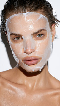Woman applying a transparent hydrating sheet mask to her face, promoting skin health and beauty through professional skincare for a refreshed, smooth, and young appearance