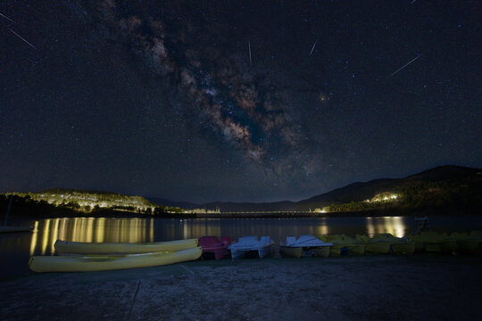 Milky way galaxy over beznar reservoir with shooting stars and parked pedal boats at night