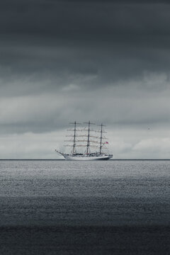 View of a large sailing ship navigating the calm sea under a dramatic dark cloudy sky in Merikula, Harju maakond, Estonia.