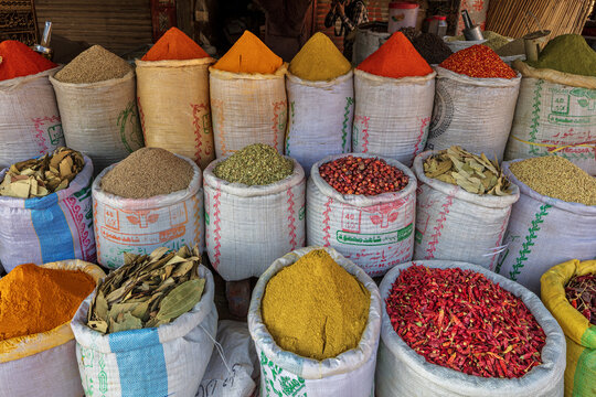 View of Akbari Mandi market in Lahore, featuring colorful piles of spices, dried red chilies, and grains stored in large woven sacks, Lahore, Punjab, Pakistan.