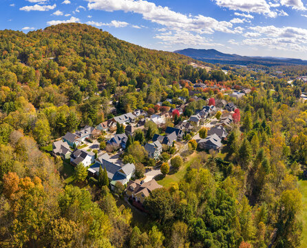 Rural homes overlooking colorful mountain forests near Asheville, North Carolina. Peak autumn foliage creates breathtaking landscape around peaceful community.