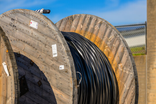 Large wooden cable reels with black industrial conduit.