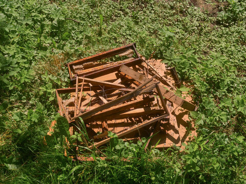 Pile of wooden honeycomb frames on a green grass. Result of wild bear attack on a small portable beehive left close to forest. All sweet staff is gone, everything is damaged by huge beast.