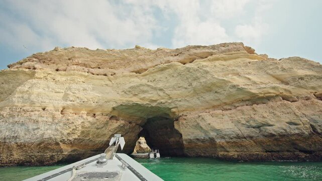 View from a tour boat approaching a natural limestone sea cave with turquoise water near Carvoeiro on the Algarve coast.