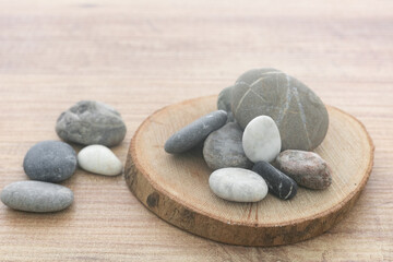 Obraz na płótnie Canvas Natural sea pebbles pile on round wooden slice background.