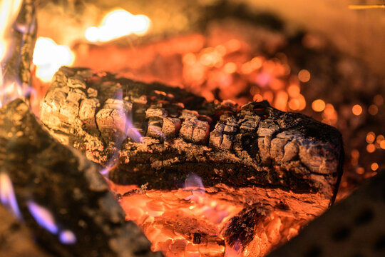 Burning firewood logs glowing with flames and embers.