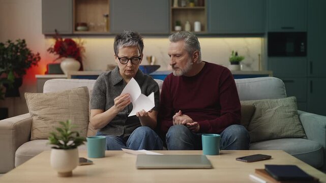 Mature woman and her husband reading official letter, upset about rejected visa