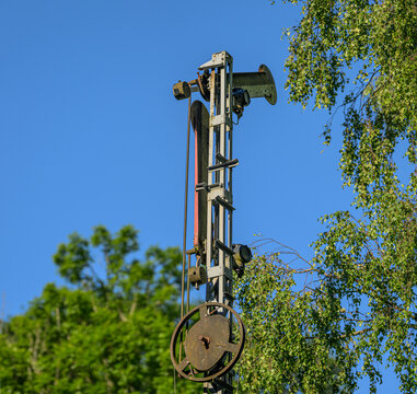 Vintage railway signal tower rising above green trees and blue sky.