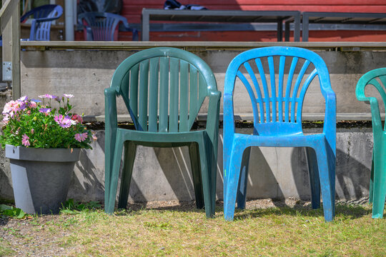 Colorful plastic patio chairs with summer flowers outdoors.