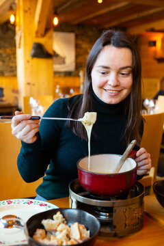 Portrait of cheerful woman eating traditional Swiss cheese fondue