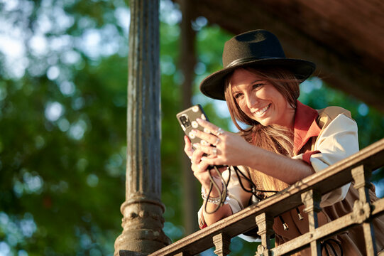 Young woman smiling using smartphone on balcony