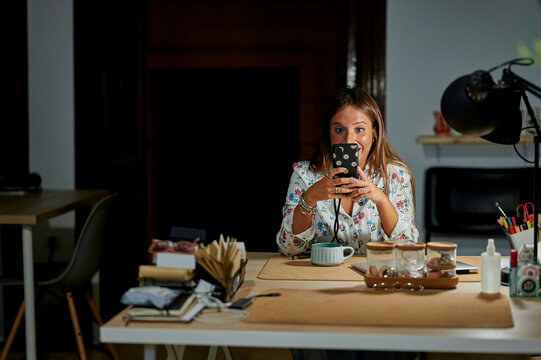 Excited woman using phone at office desk