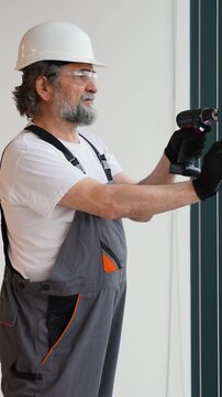 Senior construction worker using cordless screwdriver
