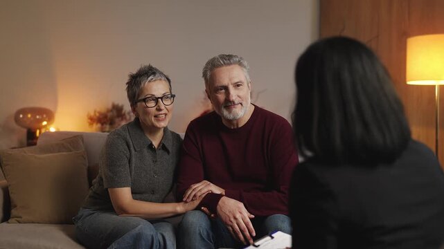 Smiling middle-aged couple thanking marriage counselor and shaking hands