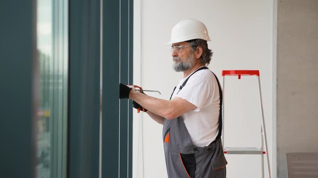 Construction worker sealing a window frame with caulking gun