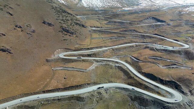 Aerial drone footage overlooking the dramatic switchbacks of Too-Ashuu Pass in Kyrgyzstan, showcasing vehicles navigating the winding Bishkek&ndash;Osh highway through the Tian Shan.
