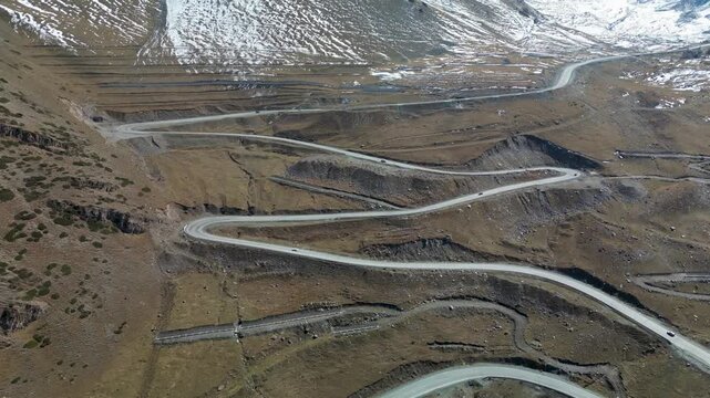 Aerial drone footage of the winding Too-Ashuu Pass in Kyrgyzstan, featuring cars and trucks traveling along the dramatic Bishkek&ndash;Osh mountain highway through the Tian Shan.