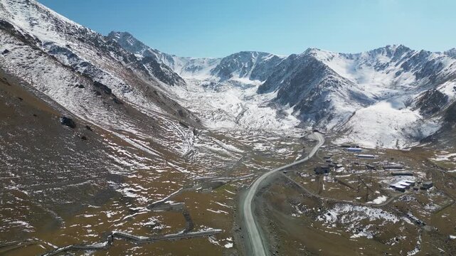 Aerial drone footage of the Bishkek&ndash;Osh highway leading into the snow-covered Tian Shan mountains at Too-Ashuu Pass, Kyrgyzstan, showcasing dramatic alpine scenery and rugged terrain.