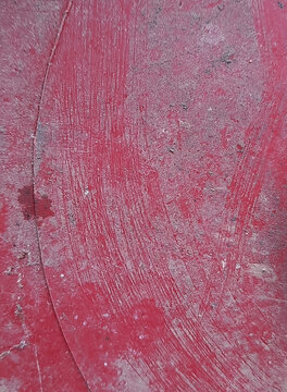 Damaged red plastic backdrop with rough gritty texture and brush marks.