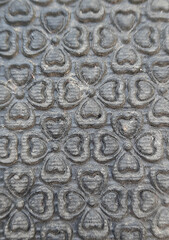 Obraz premium Embossed four-leaf clover heart pattern on dark grey rubber mat surface.