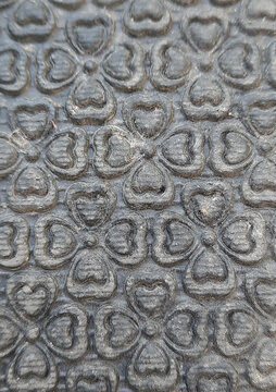 Embossed four-leaf clover heart pattern on dark grey rubber mat surface.