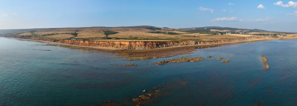 Aerial panoramic view of Compton Bay and Brook Chine Beach on the south-west coast of the Isle of Wight, England, showcasing dramatic cliffs, golden sands, turquoise water, and the spectacular coast
