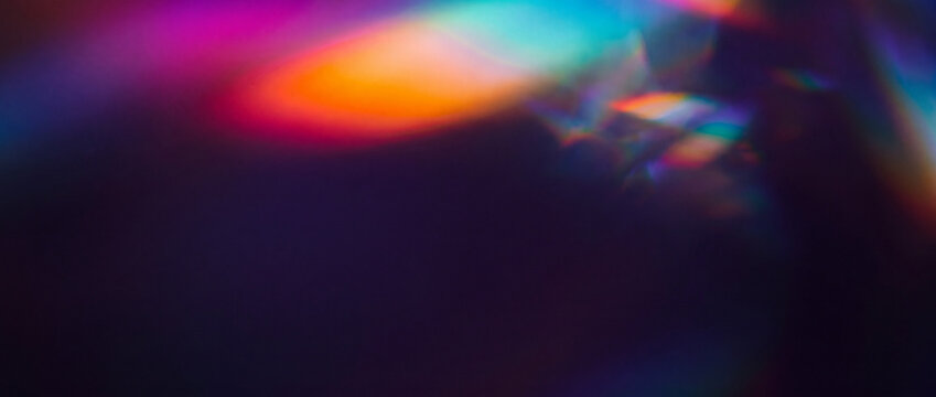 Prism light leak overlay on dark background with vibrant neon rainbow bokeh refractions, crystal spectrum lens flare, and soft blurred gradients for creative abstract design