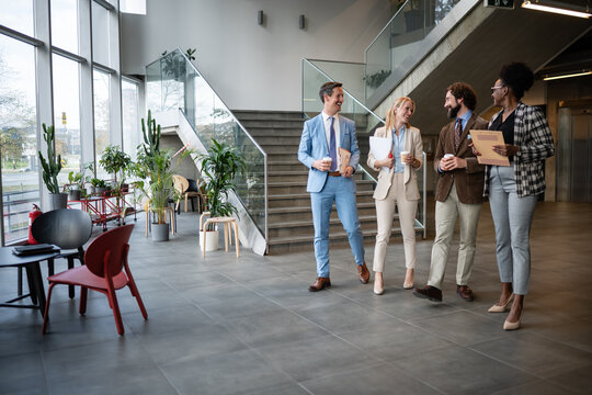 Diverse business professionals walking, talking, and networking in modern office lobby