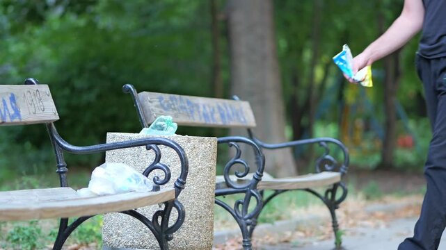 Young man responsibly throwing garbage into a park trash can