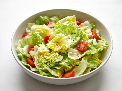 Fresh garden green salad with lettuce and cherry tomatoes in a white bowl
