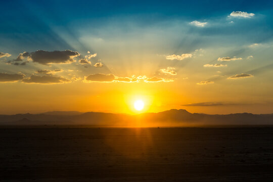 View of the sun setting over the volcanic landscape of Erta Ale with golden rays illuminating the horizon in Zone 2, Afar, Ethiopia.