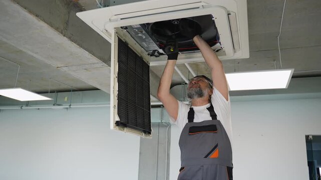 Technician repairing ceiling air conditioner unit