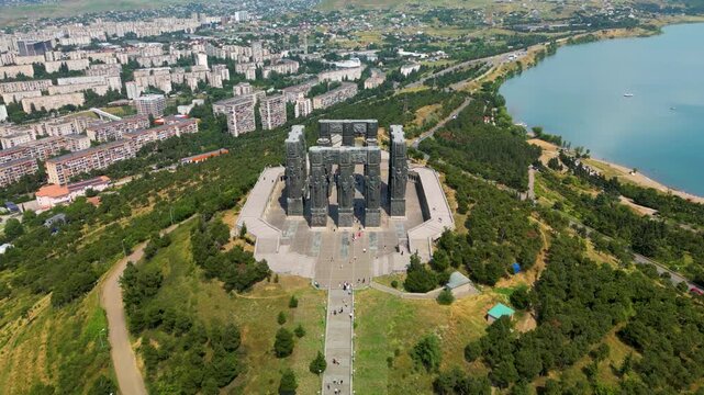 Aerial drone footage of the Chronicle of Georgia in Tbilisi, Georgia, featuring the monumental memorial, grand staircase filled with visitors and panoramic views above the Tbilisi Sea.