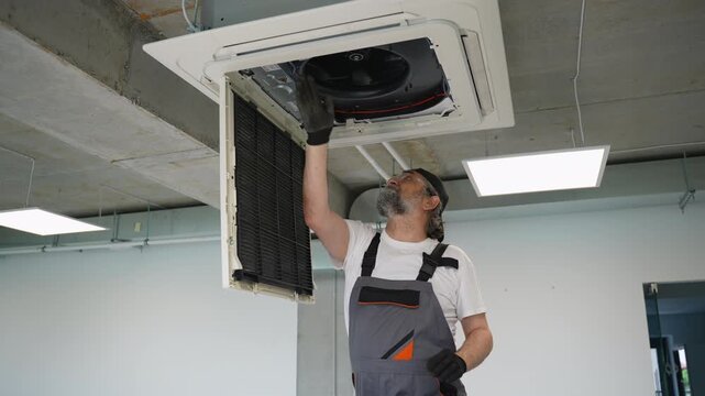 Senior technician installing cassette air conditioner filter