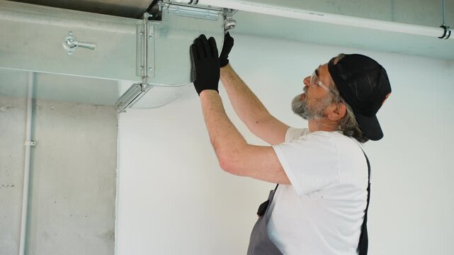 Senior hvac technician installing galvanized steel air duct