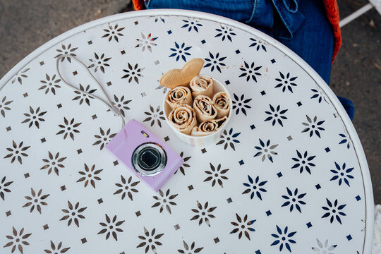 Rolled ice cream and retro compact camera on decorative outdoor cafe table