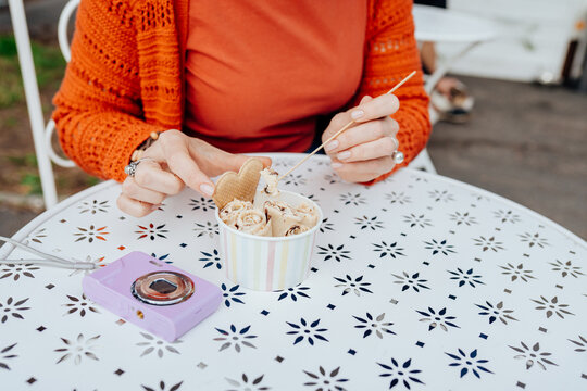 Woman eating handmade rolled ice cream at outdoor cafe table, close-up