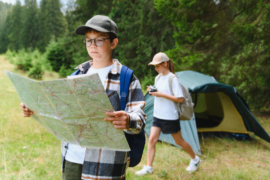 Boy holding map navigating during forest adventure camping