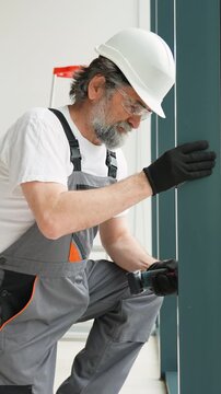 Senior construction worker drilling into a metal frame