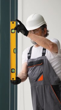 Older worker using spirit level on wall