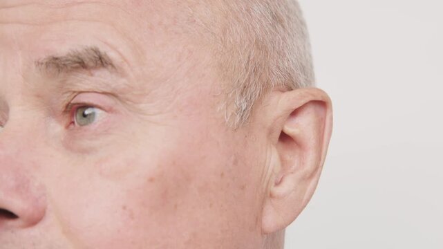 bald man hearing or listening deeply, ear with pained expression, discomfort loud noise, age-related hearing loss, Emotional portrait, discomfort loud noise, Environmental noise, reaction loud sounds