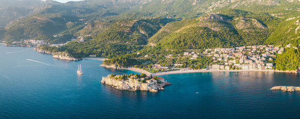 Obraz premium Aerial panoramic view of Sveti Stefan island, turquoise Adriatic Sea, coastal beaches and green mountains on the Budva Riviera in Montenegro.