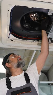 Professional technician inspecting ceiling ventilation system fan