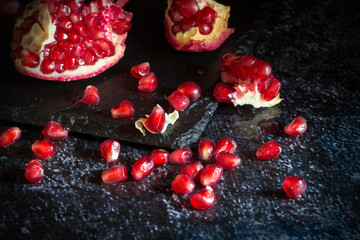 Fresh Pomegranate placed in old silver cup full of seeds in backlit with dark and moody tone © Siyue