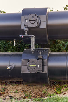 View of large black industrial pipes with valves and chains, part of the district heating system in Esbjerg, Denmark.