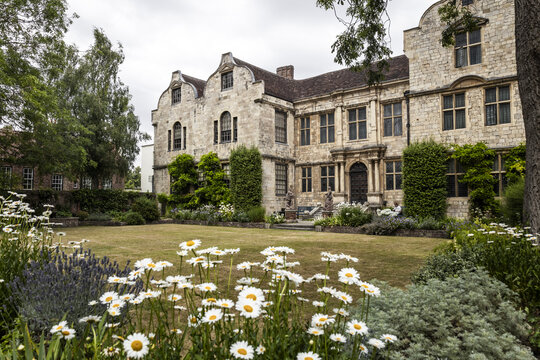 View of the historic Gray's Court building with its stone facade and manicured garden featuring blooming daisies and lavender in York, England, United Kingdom.