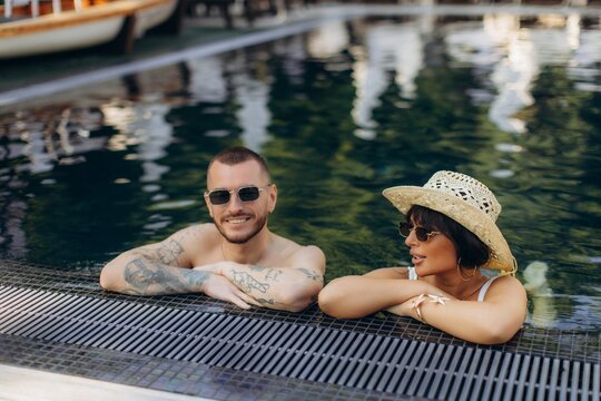 Happy couple relaxing enjoying summer vacation in swimming pool