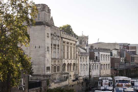 View of the historic Guildhall building along the River Ouse with stone masonry, arched windows, and moored boats in York, England, United Kingdom.