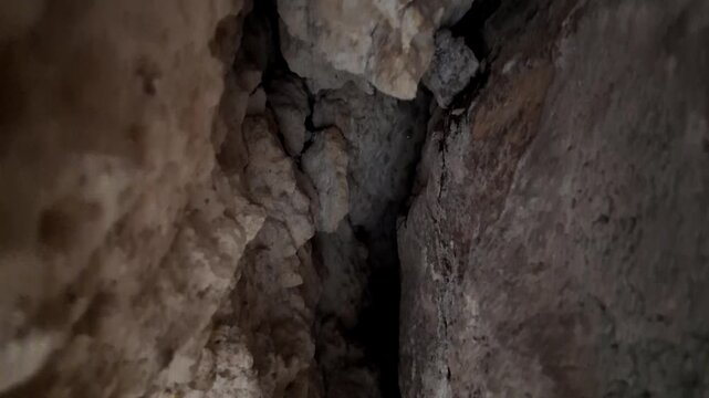 Xemxija, Malta 29.07.2026 - Heritage trail, Roman Baths, shelf like cut in the stone Dark cave walls show rough, textured surfaces. Greenish moss grows on damp, uneven stone. Light filters through nar