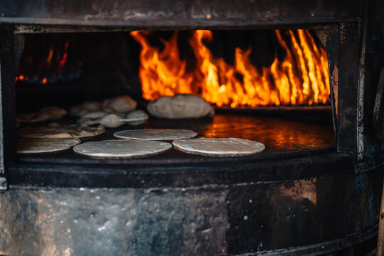 View of local bread baking on a hot metal surface inside a traditional wood-fired oven with visible flames in Siwa, Marsa Matrouh Governo, Egypt.